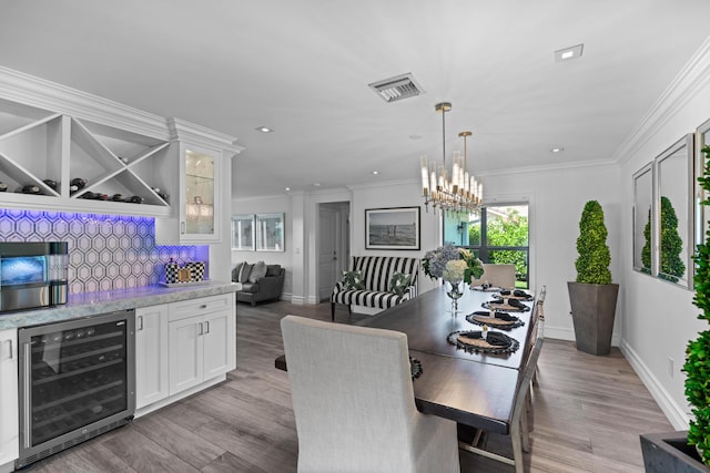 6204 Celadon Cir, Palm Beach Gardens, FL 33418 - dining space featuring beverage cooler, a chandelier, light wood-style floors, crown molding, and recessed lighting