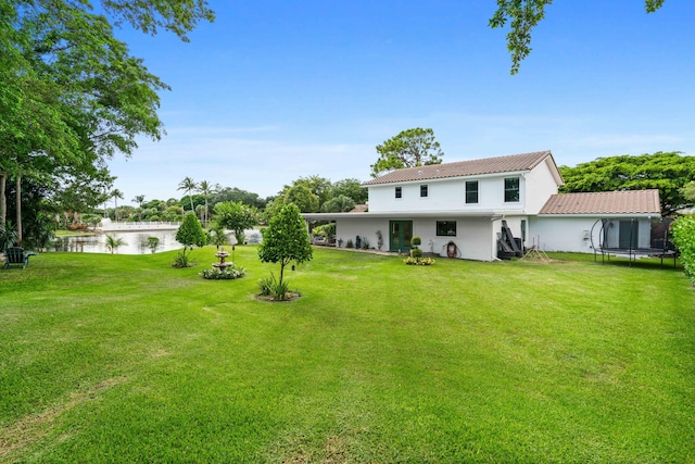 6204 Celadon Cir, Palm Beach Gardens, FL 33418 - rear view of house featuring a trampoline, a water view, and a yard