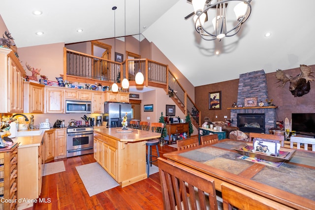 kitchen with a chandelier, decorative light fixtures, a center island, a fireplace, and appliances with stainless steel finishes