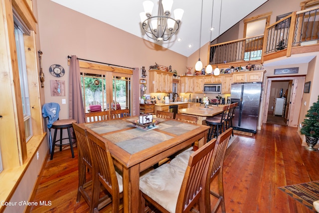 dining space featuring high vaulted ceiling, a notable chandelier, sink, and hardwood / wood-style flooring