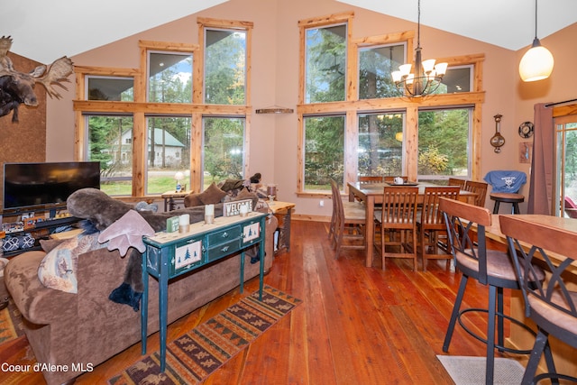 living room featuring a healthy amount of sunlight, dark wood-type flooring, a notable chandelier, and high vaulted ceiling