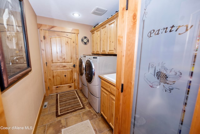 laundry room with light tile floors, washing machine and dryer, and cabinets