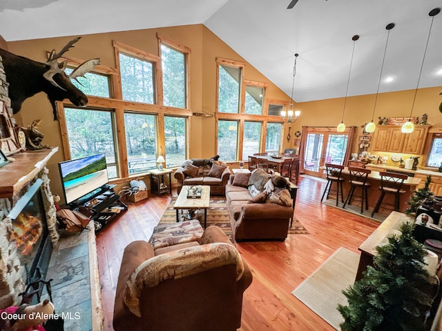 living room with a chandelier, light hardwood / wood-style flooring, and high vaulted ceiling