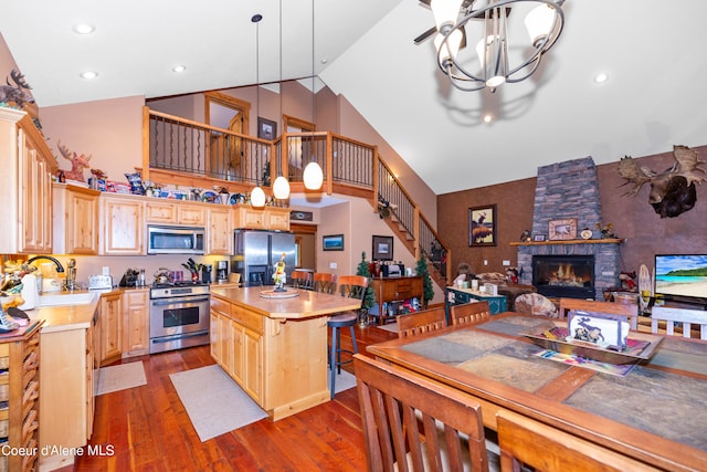 kitchen featuring stainless steel appliances, a kitchen island, decorative light fixtures, a fireplace, and an inviting chandelier