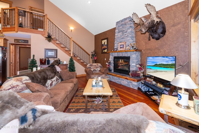 living room with high vaulted ceiling, dark hardwood / wood-style floors, and a stone fireplace