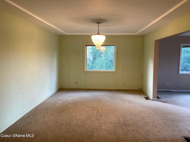 carpeted empty room with an inviting chandelier