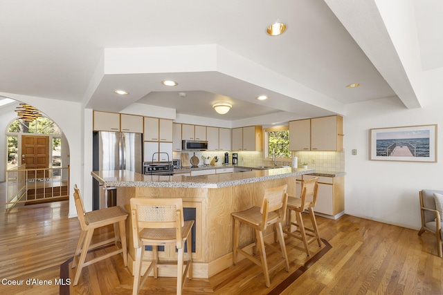 2772 W Lutherhaven Rd, Coeur Dalene, ID 83814 - kitchen with light wood-style floors, stainless steel appliances, tasteful backsplash, and a kitchen breakfast bar