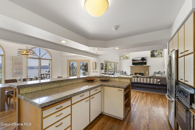 2772 W Lutherhaven Rd, Coeur Dalene, ID 83814 - kitchen featuring freestanding refrigerator, a tile fireplace, cream cabinetry, and black oven