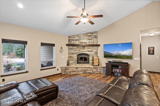 living room featuring a stone fireplace, ceiling fan, vaulted ceiling, and hardwood / wood-style flooring