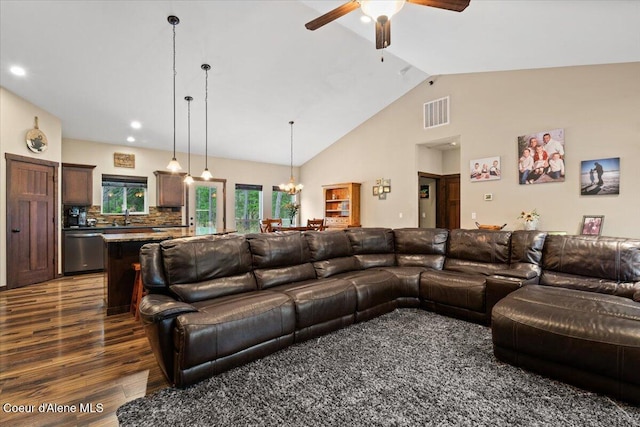 living room with sink, high vaulted ceiling, dark wood-type flooring, and ceiling fan with notable chandelier