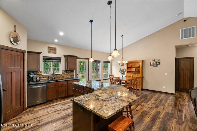 kitchen featuring a center island, sink, stainless steel dishwasher, dark hardwood / wood-style floors, and dark stone counters