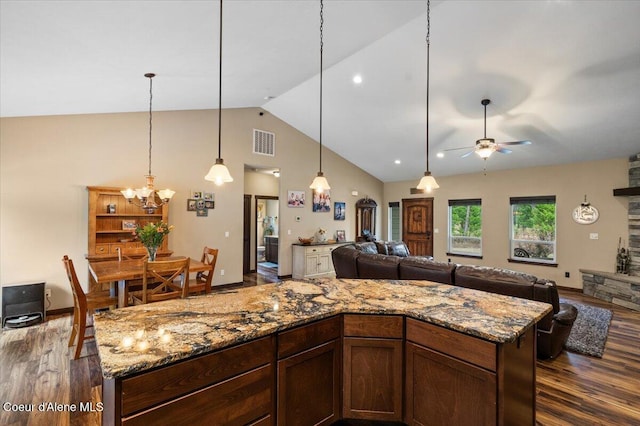 kitchen with hanging light fixtures, dark wood-type flooring, high vaulted ceiling, stone countertops, and ceiling fan with notable chandelier