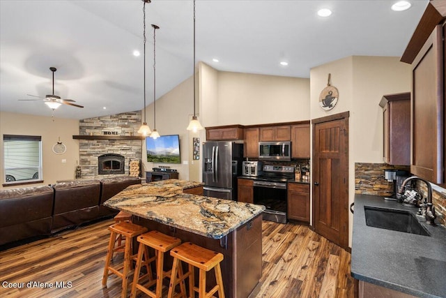 kitchen featuring light stone countertops, appliances with stainless steel finishes, dark wood-type flooring, sink, and a breakfast bar area