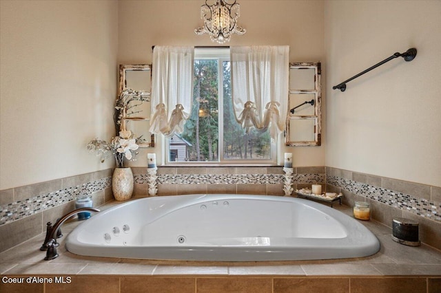 bathroom with a chandelier and tiled bath