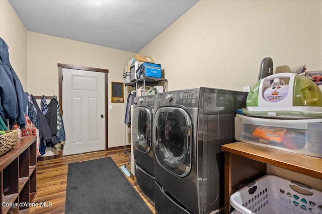 washroom with a textured ceiling, light hardwood / wood-style flooring, and washer and clothes dryer