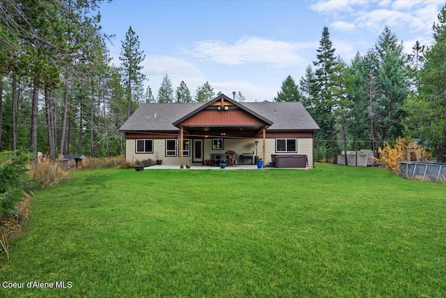 back of house featuring a patio, a hot tub, and a lawn