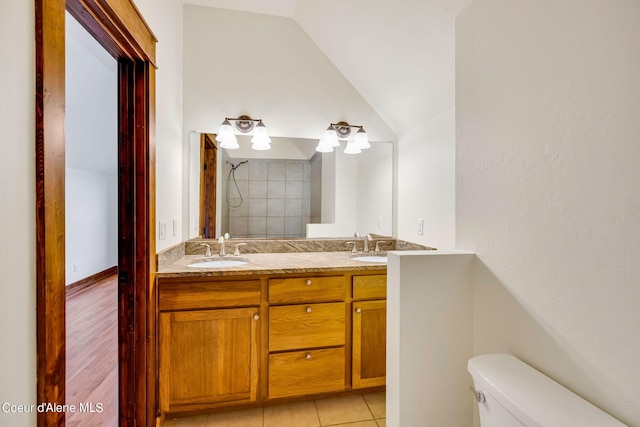 bathroom featuring toilet, large vanity, hardwood / wood-style flooring, vaulted ceiling, and double sink