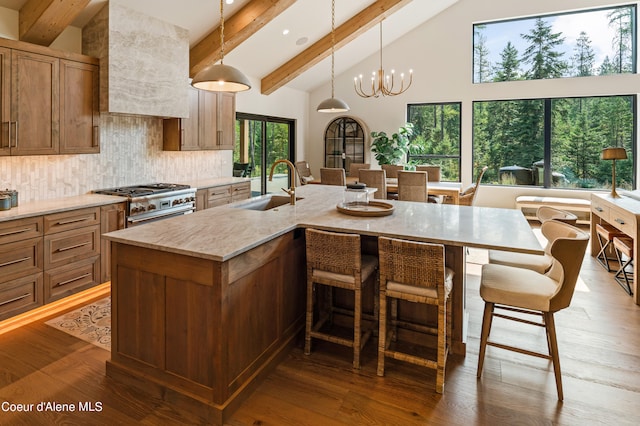 kitchen with a center island with sink, sink, decorative backsplash, and hardwood / wood-style flooring