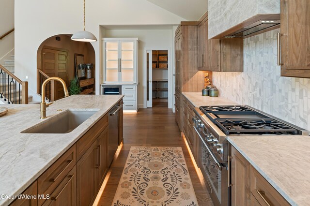 kitchen with decorative light fixtures, light stone countertops, stainless steel appliances, sink, and dark hardwood / wood-style floors