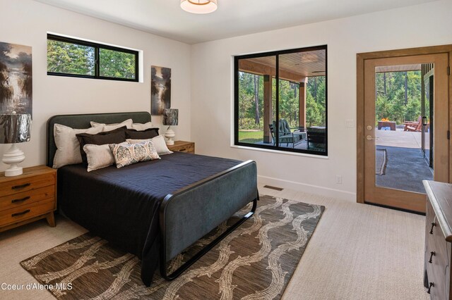 bedroom with multiple windows, light colored carpet, and access to outside