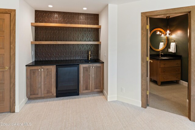 bar with beverage cooler, light carpet, decorative light fixtures, and sink