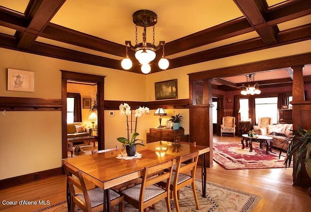 dining area with coffered ceiling, an inviting chandelier, and dark hardwood / wood-style flooring