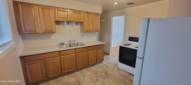 kitchen with decorative backsplash, white appliances, and sink