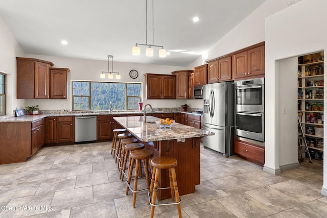 kitchen with decorative light fixtures, light stone counters, stainless steel appliances, a kitchen island with sink, and vaulted ceiling