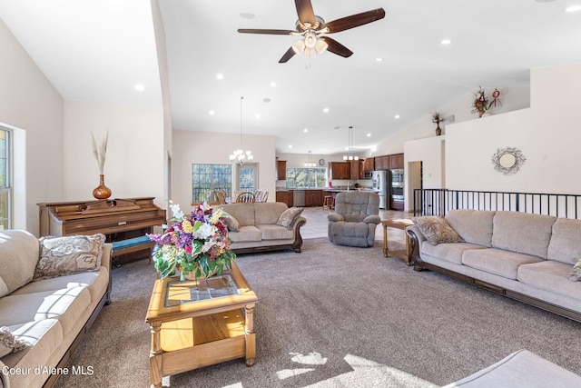 living room with high vaulted ceiling, ceiling fan with notable chandelier, and dark carpet