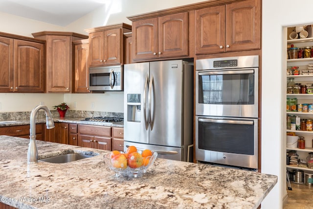 kitchen with light stone counters, appliances with stainless steel finishes, and sink