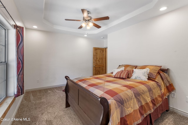 carpeted bedroom with a tray ceiling and ceiling fan