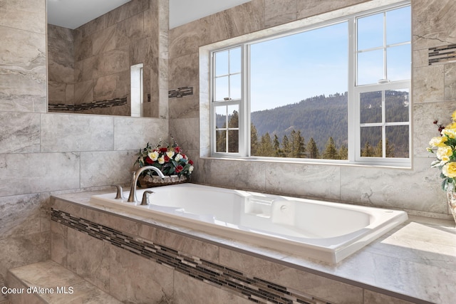 bathroom featuring tiled bath, tile walls, and a mountain view