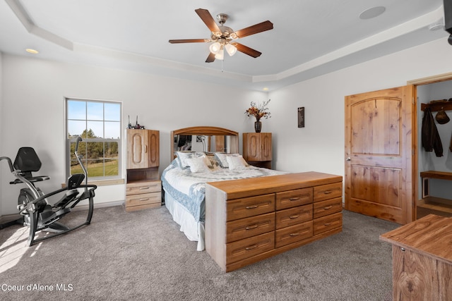 bedroom with carpet flooring, ceiling fan, and a raised ceiling