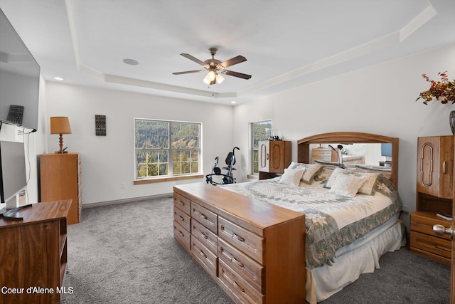 carpeted bedroom with ceiling fan and a tray ceiling