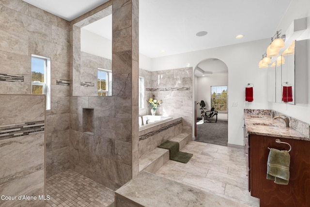 bathroom featuring plus walk in shower, vanity, and a wealth of natural light