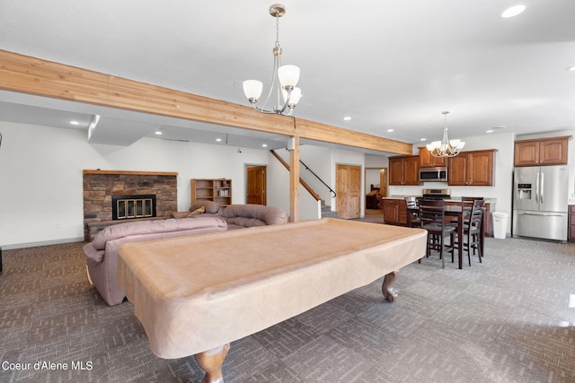 game room featuring a chandelier, pool table, a stone fireplace, and dark colored carpet