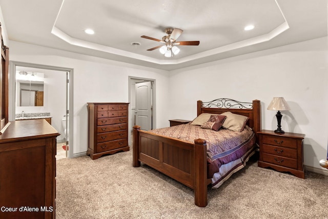 carpeted bedroom with a raised ceiling and ceiling fan