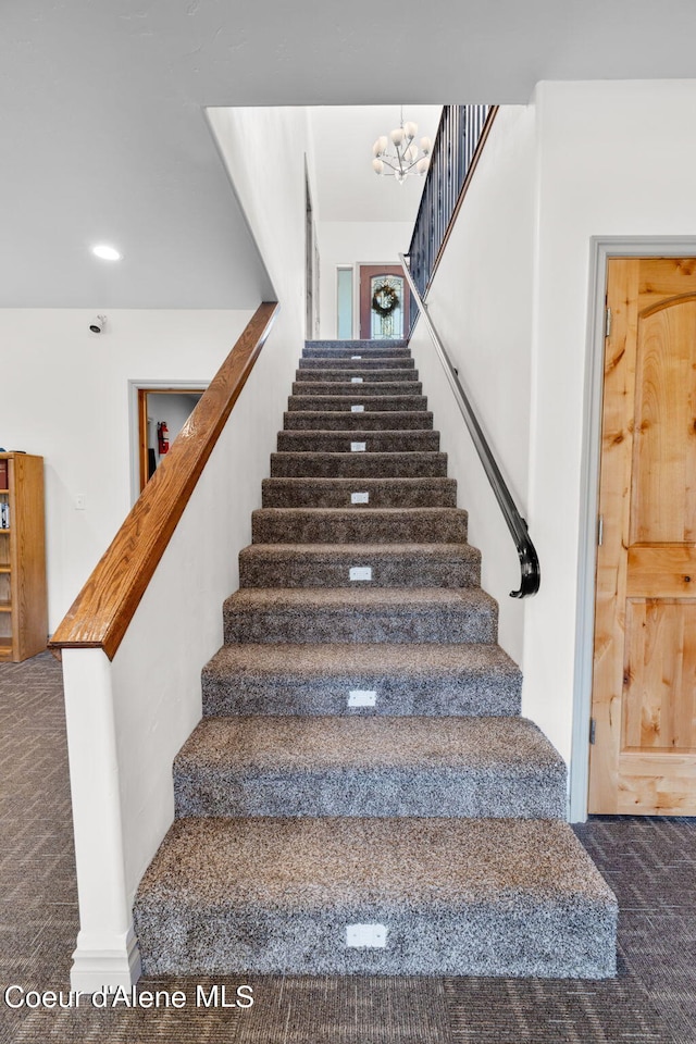 stairs featuring a notable chandelier and carpet