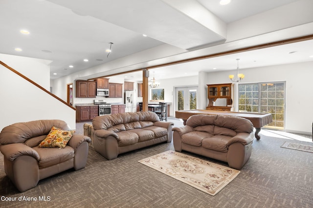 carpeted living room with a notable chandelier and pool table