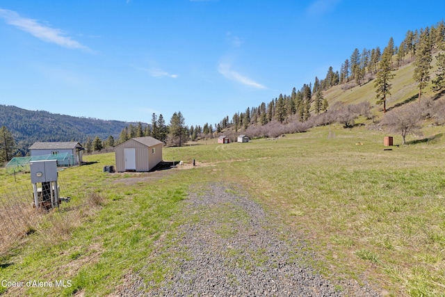 view of yard with a rural view, a mountain view, and a storage shed