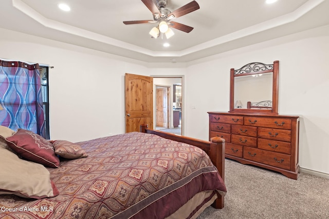 carpeted bedroom featuring ceiling fan and a raised ceiling