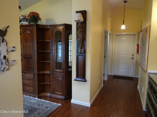 hallway with dark hardwood / wood-style floors and vaulted ceiling