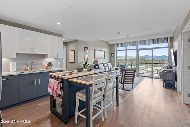 kitchen featuring white cabinets, sink, light hardwood / wood-style floors, a mountain view, and double oven range