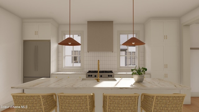 kitchen featuring plenty of natural light, built in fridge, tasteful backsplash, and hanging light fixtures