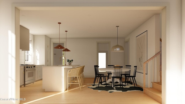 kitchen featuring plenty of natural light, gas range, light hardwood / wood-style floors, and decorative light fixtures