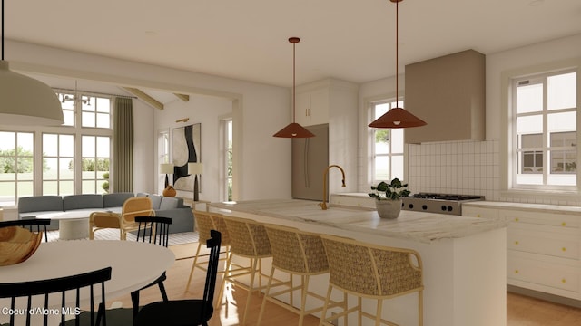 kitchen with plenty of natural light, tasteful backsplash, light stone counters, and decorative light fixtures