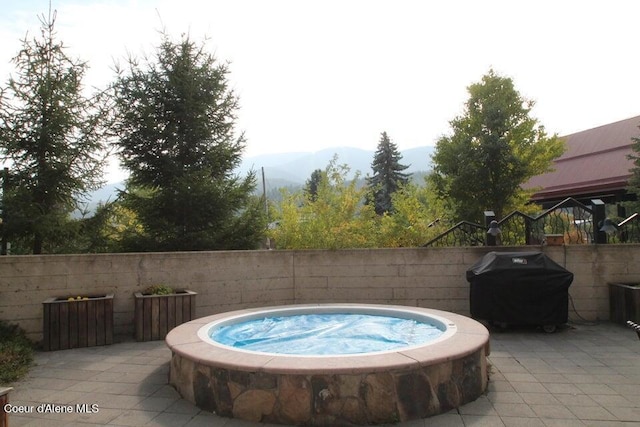 view of swimming pool with an outdoor hot tub, a grill, a mountain view, and a patio