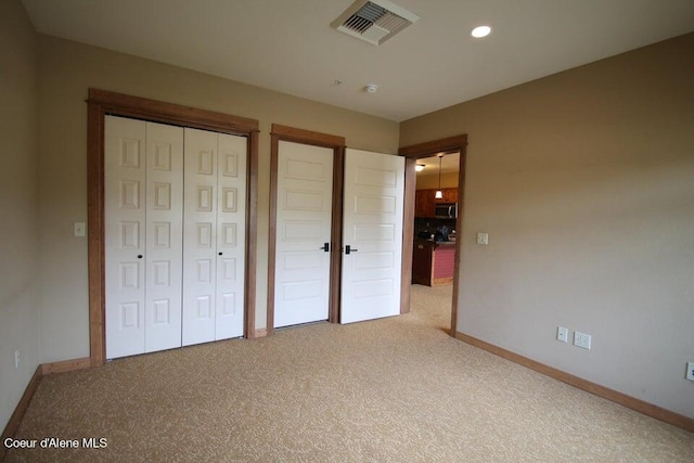 unfurnished bedroom with a closet and light carpet