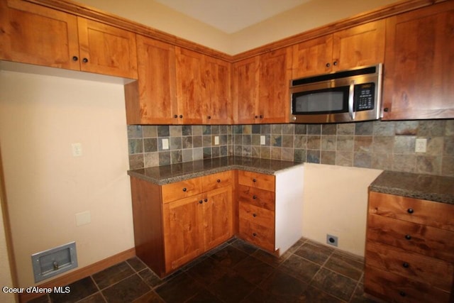 kitchen with tasteful backsplash and dark tile flooring