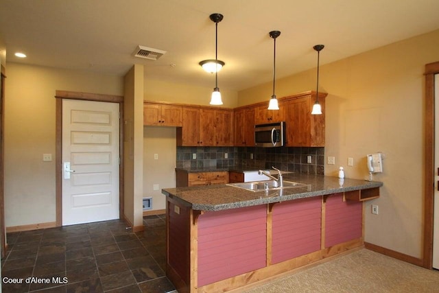 kitchen featuring decorative light fixtures, backsplash, kitchen peninsula, a kitchen bar, and sink